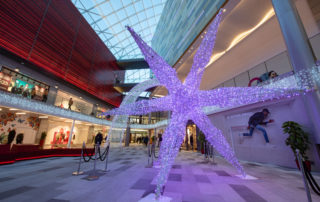 Light up colour changing shooting star motif displayed in the middle of a shopping centre.