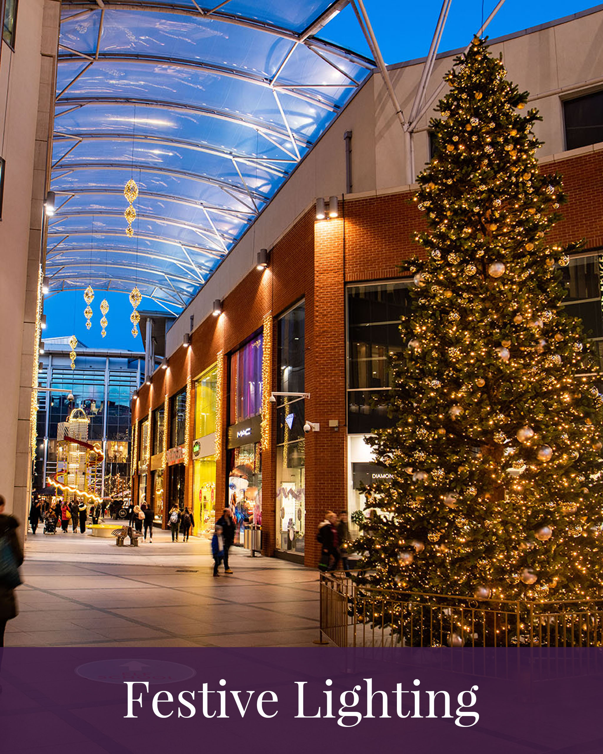 Icon of large-scale artificial green Christmas Tree displayed in the centre of a shopping centre, decorated with gold baubles and decorations and the words festive lighting at the bottom of the icon.