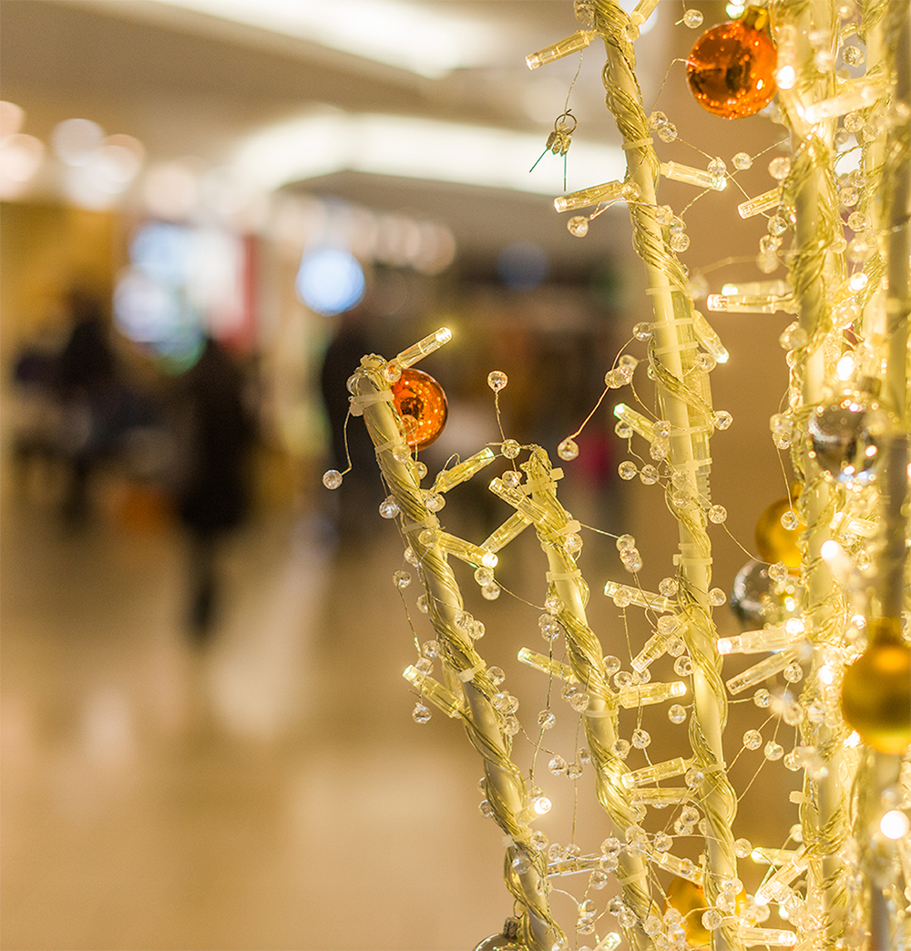 Close up of light up twig vase decorated with copper, gold, and silver baubles.