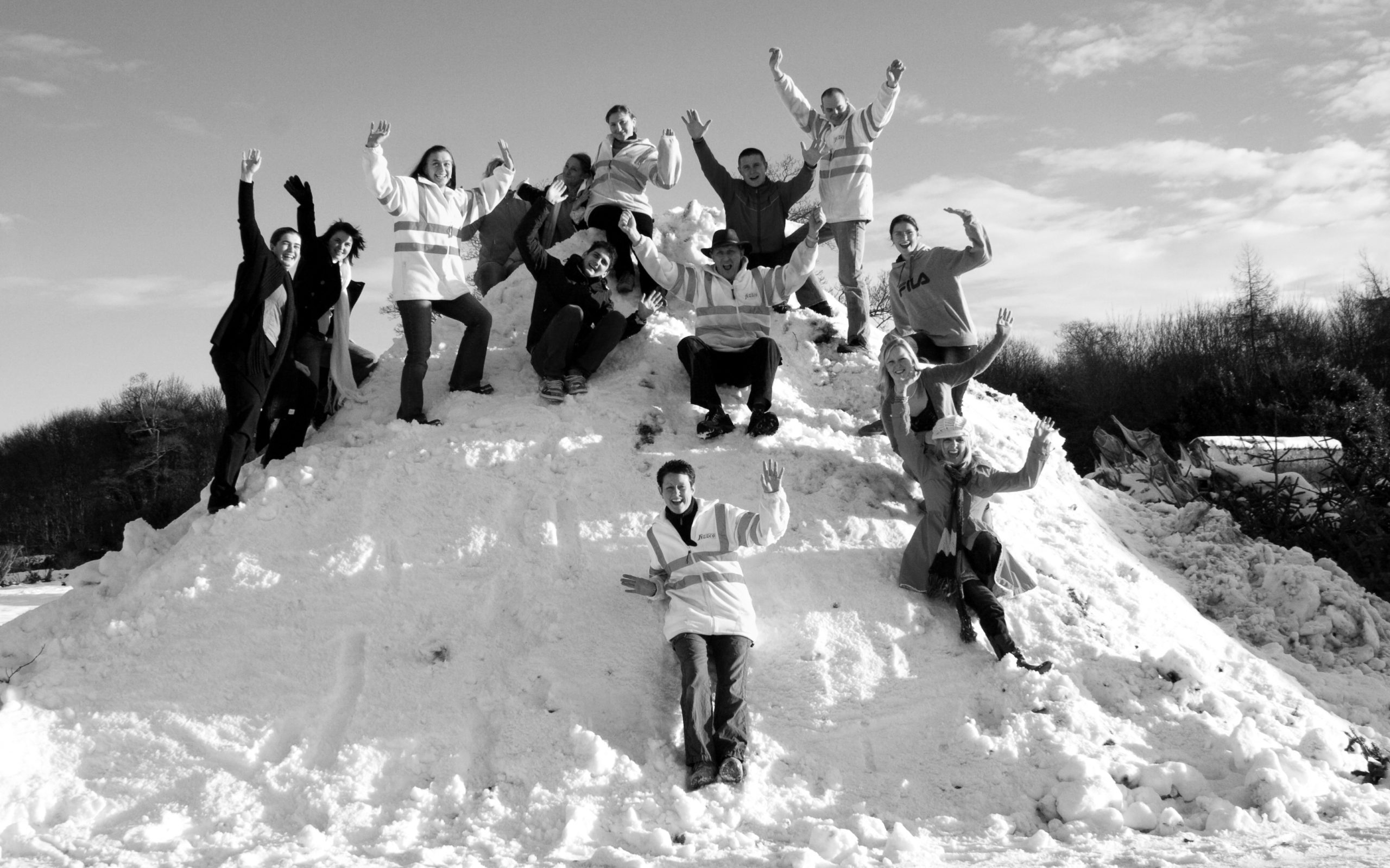 Black and white image of Fizzco staff members cheering on a hill covered in snow.