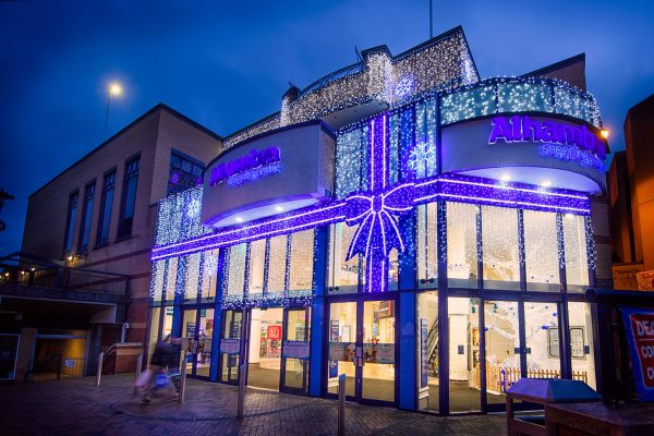 Light up blue ribbon bow with bright white curtain lights and bright white snowflake motifs on the outside wall of Alhambra Shopping Centre.