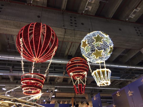 Two red hot air balloon light up 3D motifs and one white with gold stars hot air balloon motif, all suspended from the ceiling.