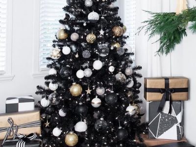 A black Christmas tree decorated with white lights and white, black and gold baubles.