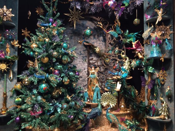 Christmas display featuring a green artificial Christmas Tree decorated with gold, green and purple baubles, and green and gold fairies, flowers and insects displayed around it.