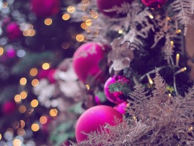 Close up image of Christmas decorations on a tree, showing hot pink baubles and beige coloured fauna.