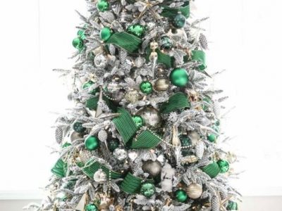 A flocked artificial Christmas Tree decorated with green and silver baubles and green ribbon.