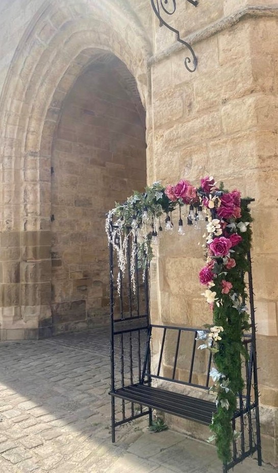 Selfie bench decorated with greenery and pink roses displayed outside Lincoln Castle.