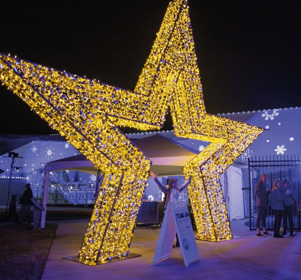 3D light-up gold star motif featured outside an event as a part of a Christmas display.