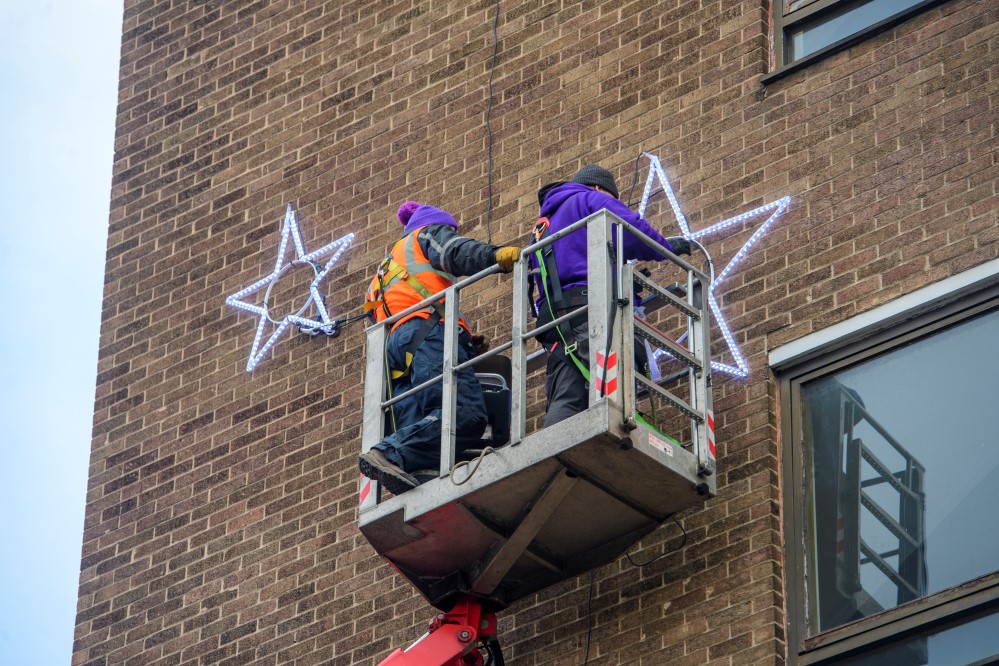 Light-up blue star motifs displayed outside County Hospital being installed by members of Fizzco Projects' installation team.