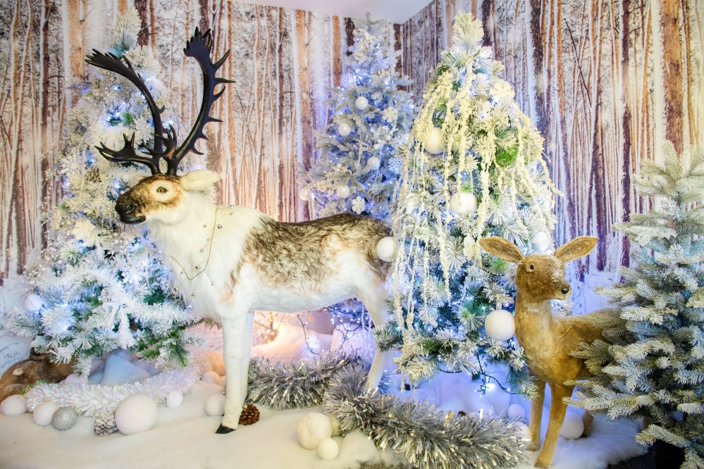 Christmas display scene featuring four flocked Christmas trees, two reindeer, tinsel and fake snow.