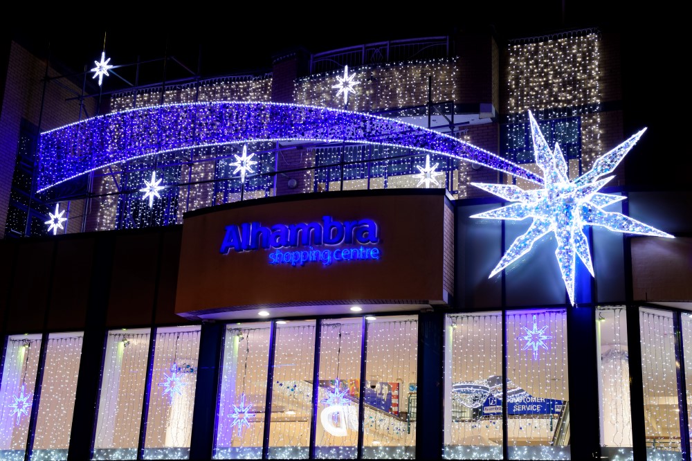 Christmas display on the outside of Alhambra shopping centre, with bright white curtain light across the windows and a white and blue shooting shar light on the outside building.