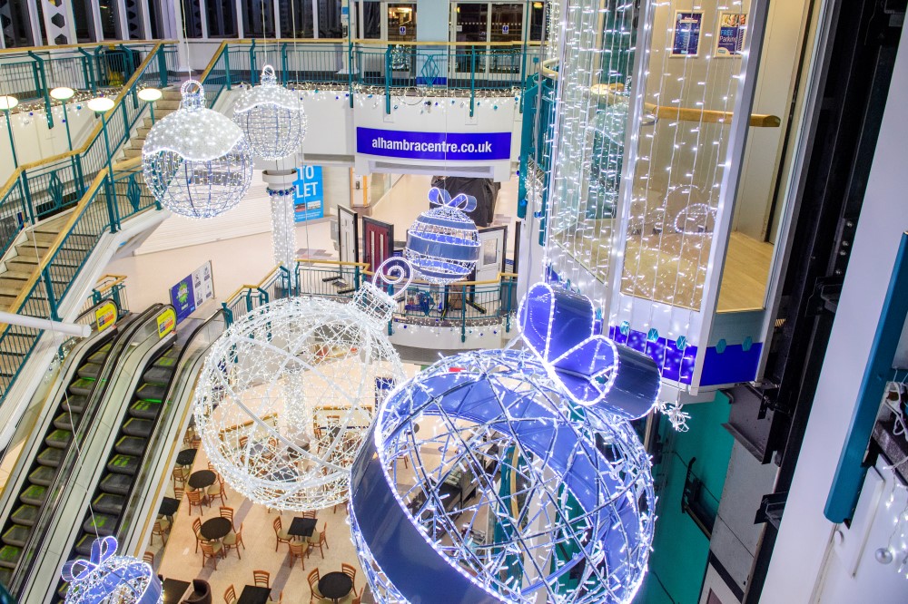 A Christmas display at Alhambra Shopping Centre featuring 3D bauble motifs in bright white and blue colours, suspended from the ceiling.