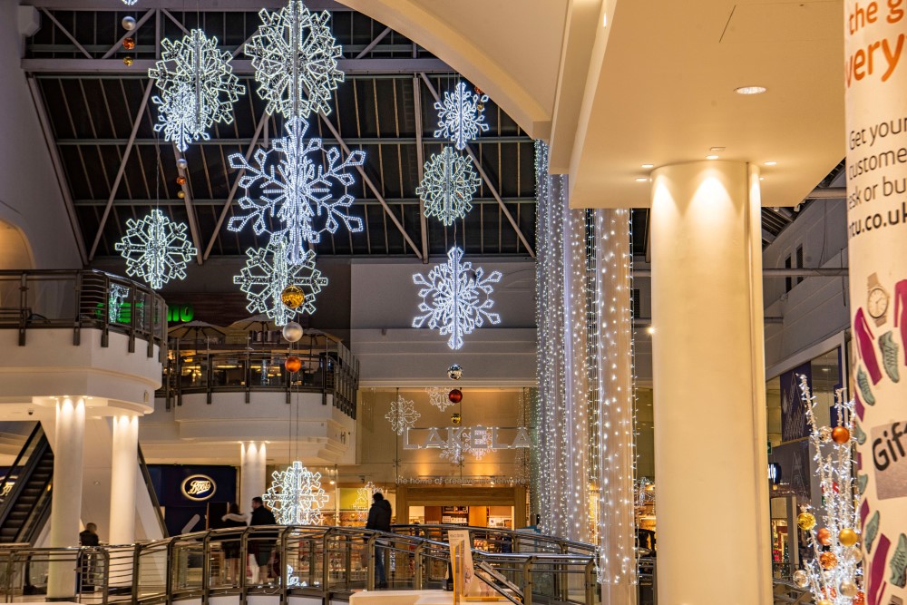 Bright white snowflake motifs suspended from the ceiling and bright white curtain lights wrapped around the pillars in the shopping centre.