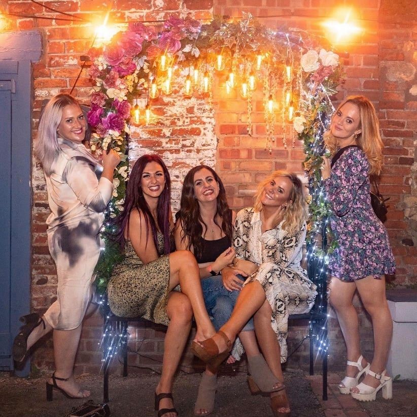 Flower arch selfie bench with friends posing for a photograph, displayed at Craft bar in Lincoln.