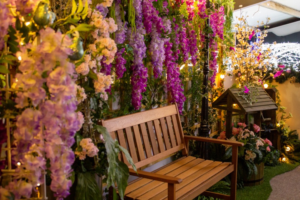 A light-up pink, purple, and green floral wall canopy display and bench scene designed by Fizzco Projects.