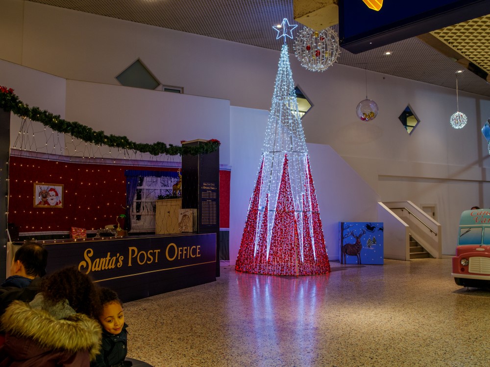 Shopping Centre Christmas display featuring Santa's post office desk, a red and white light-up Cone Christmas Tree, and light-up round hanging motifs.