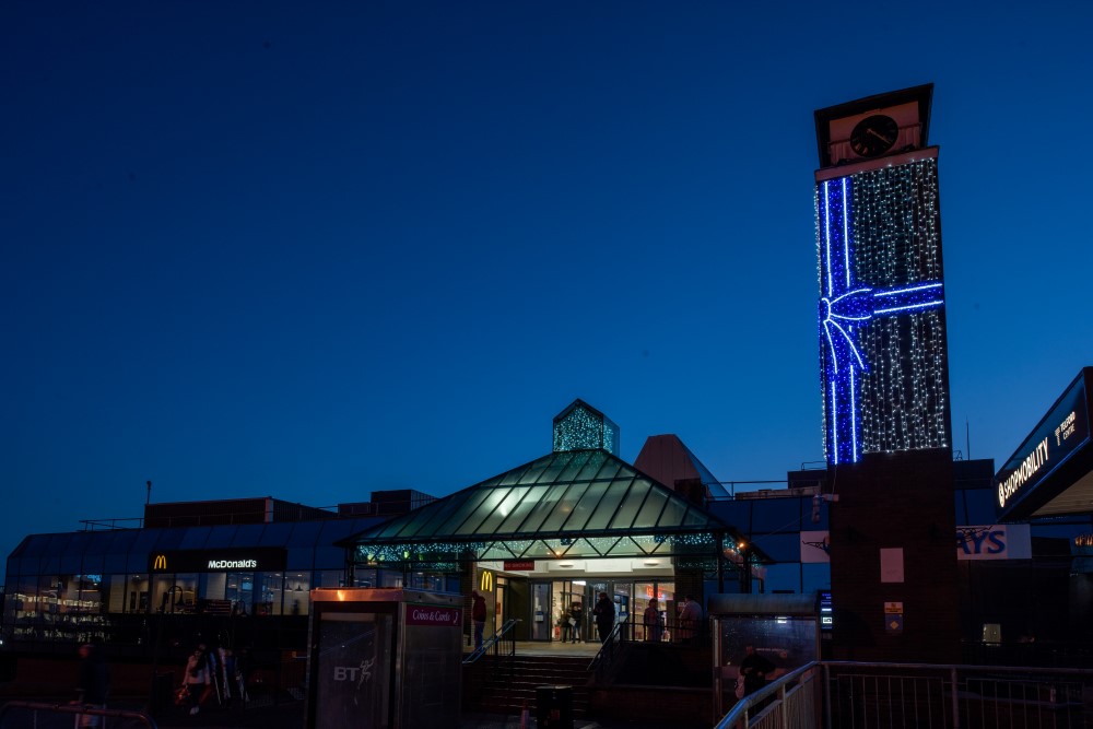 Bright white curtain lights and a blue light up ribbon displayed on the outside tower of Telford Shopping Centre as a part of their Christmas display.