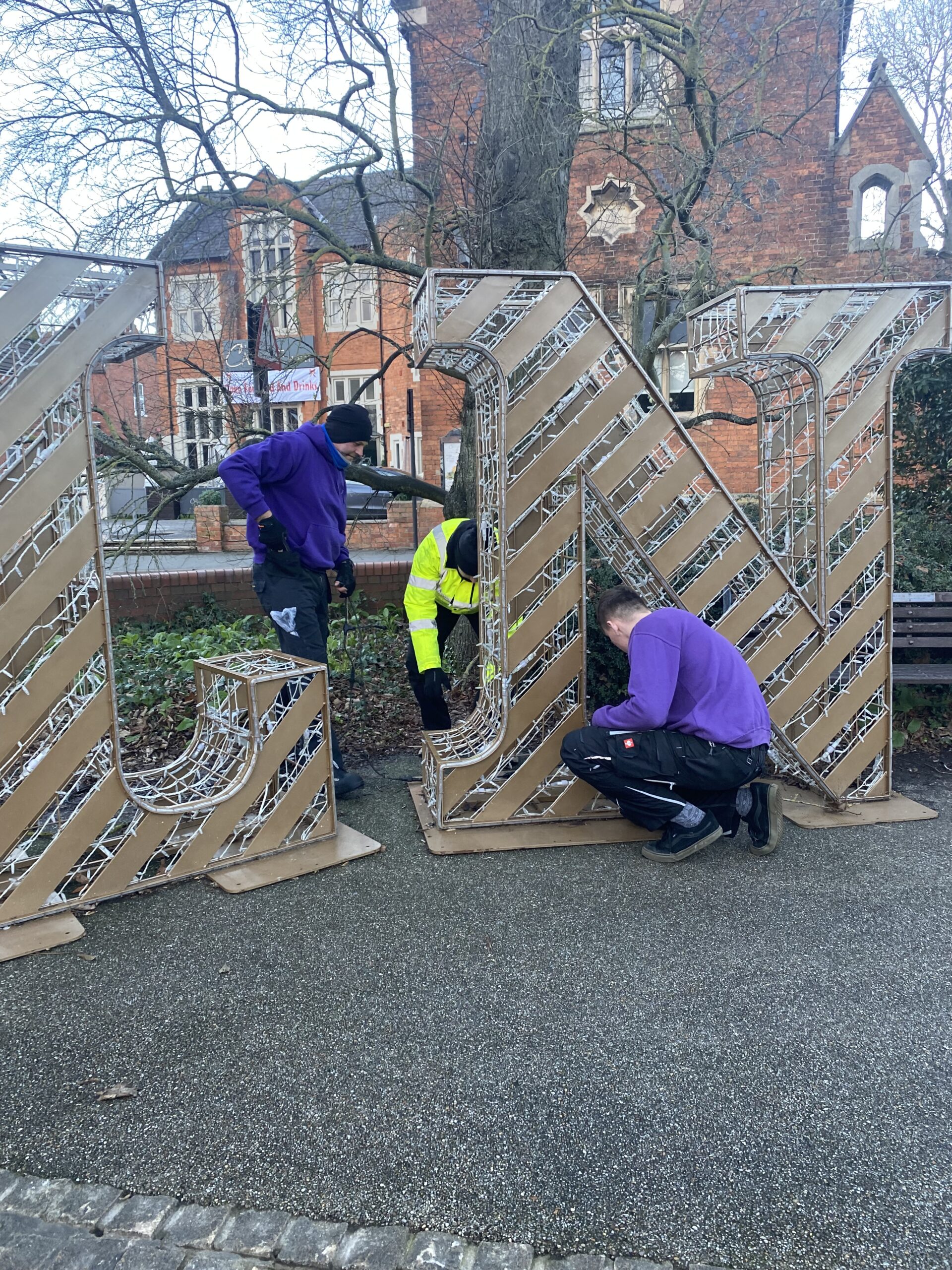 Two members of Fizzco's installation team uninstalling the gold light up LINCOLN letters from Lincoln's Christmas display.