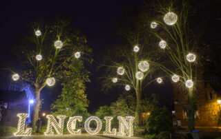 Town Christmas Lights featuring aurora balls placed in trees and Light up Lincoln letters.